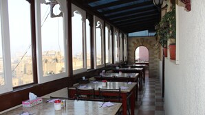 Ein Restaurant mit Tischen, Stühlen, großen Fenstern und einem karierten Boden.