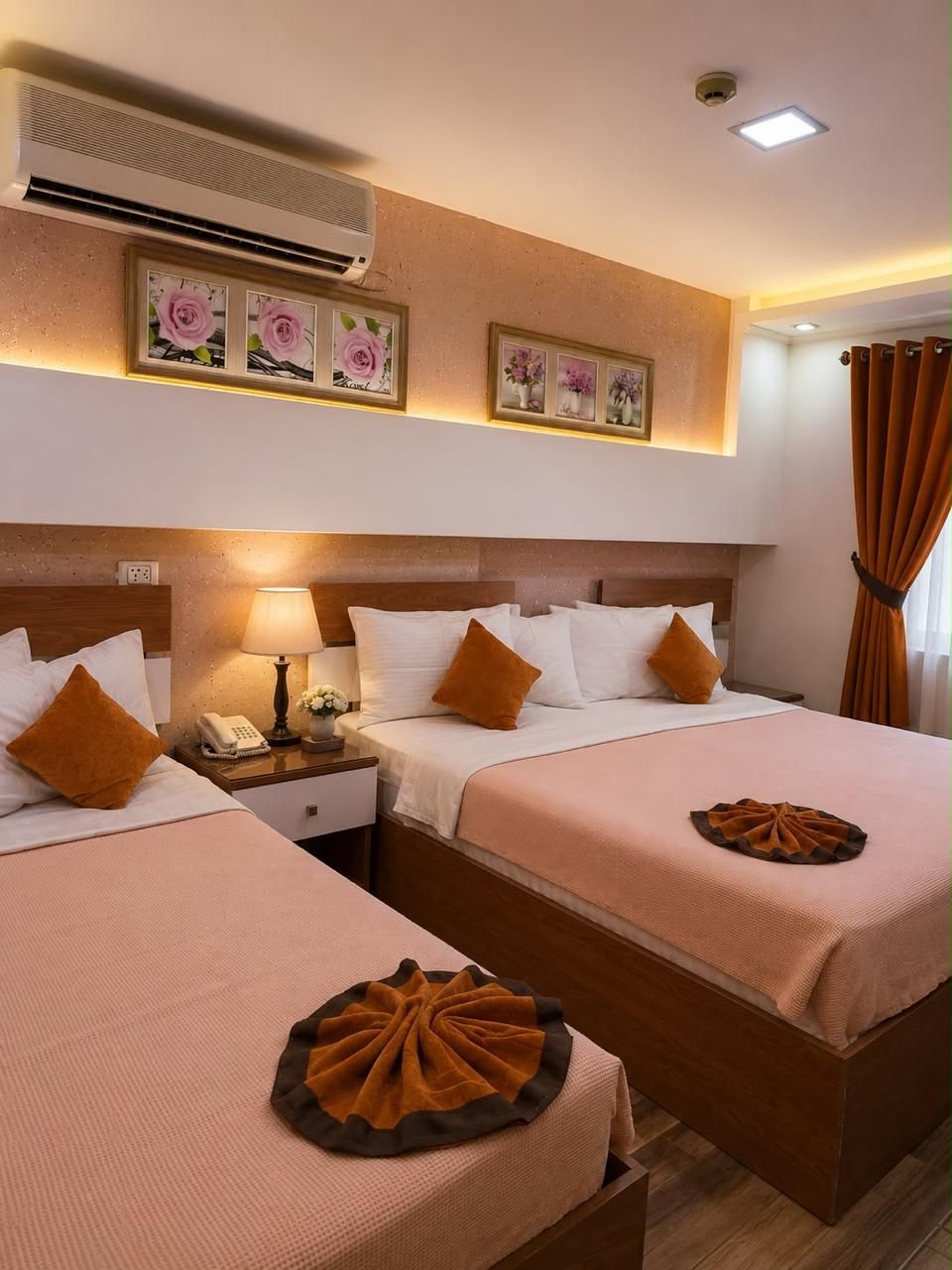 Une chambre d’hôtel avec deux lits, une table de chevet avec une lampe, un téléphone et un objet décoratif posé sur les lits.