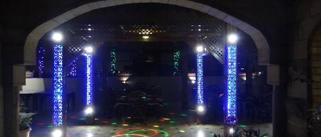 An indoor area with a tiled floor, a central circular light pattern, and decorative columns with blue lighting.