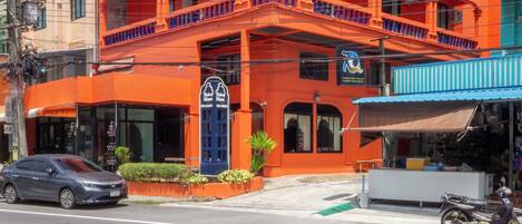 Un edificio de varios pisos con balcones, una puerta azul y un letrero.