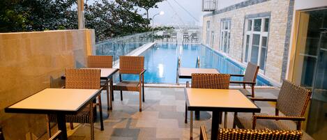 A rooftop pool area with seating and a view of the city.