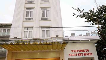 A hotel with a sign reading "Welcome to Night Sky Hotel" and a car parked in front.
