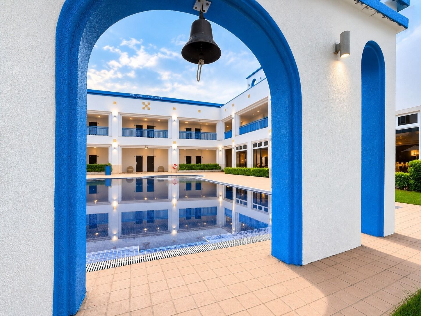 A hotel with a central pool, multiple balconies, and a bell tower.