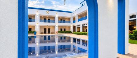 A hotel with a central pool, multiple balconies, and a bell tower.