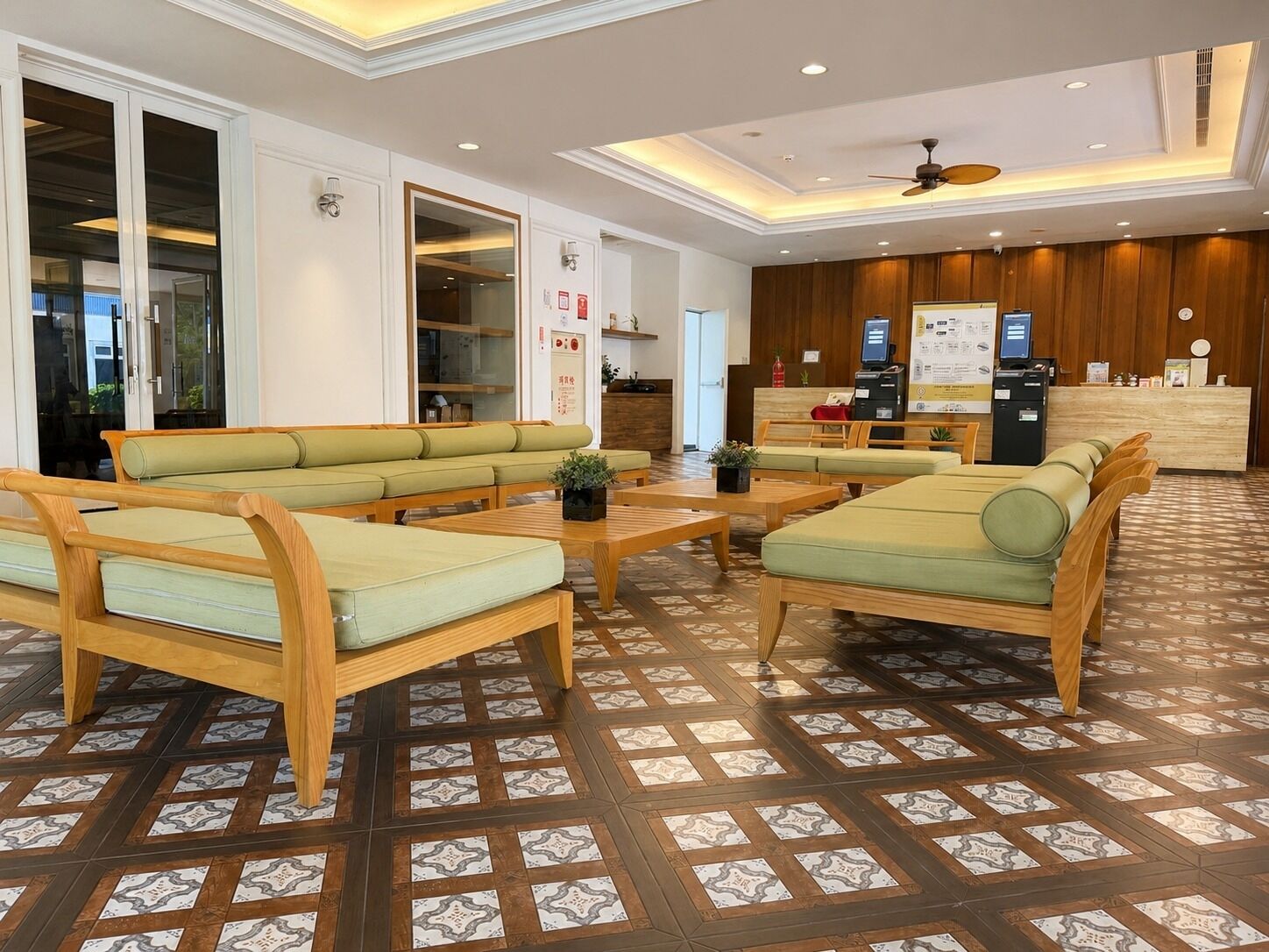 A hotel lobby with seating areas, a reception desk, and a patterned floor.
