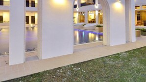 A modern building with a swimming pool, white arches, and a tree. - J Resort (Chishang)