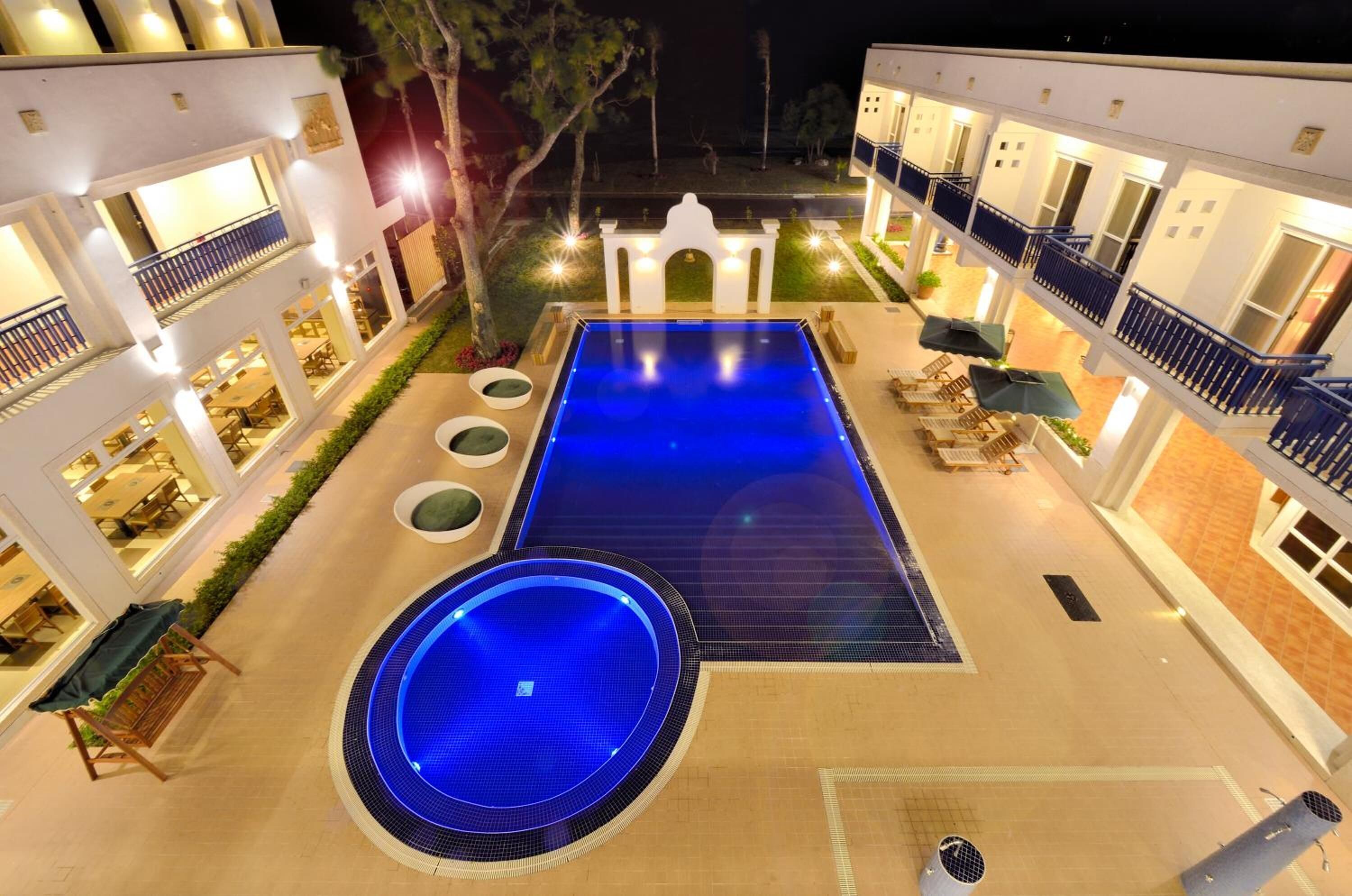 A rooftop pool area with a rectangular pool, a circular hot tub, and lounge seating.