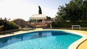 Ein Swimmingpool mit Liegestühlen und einer Laube im Hintergrund.