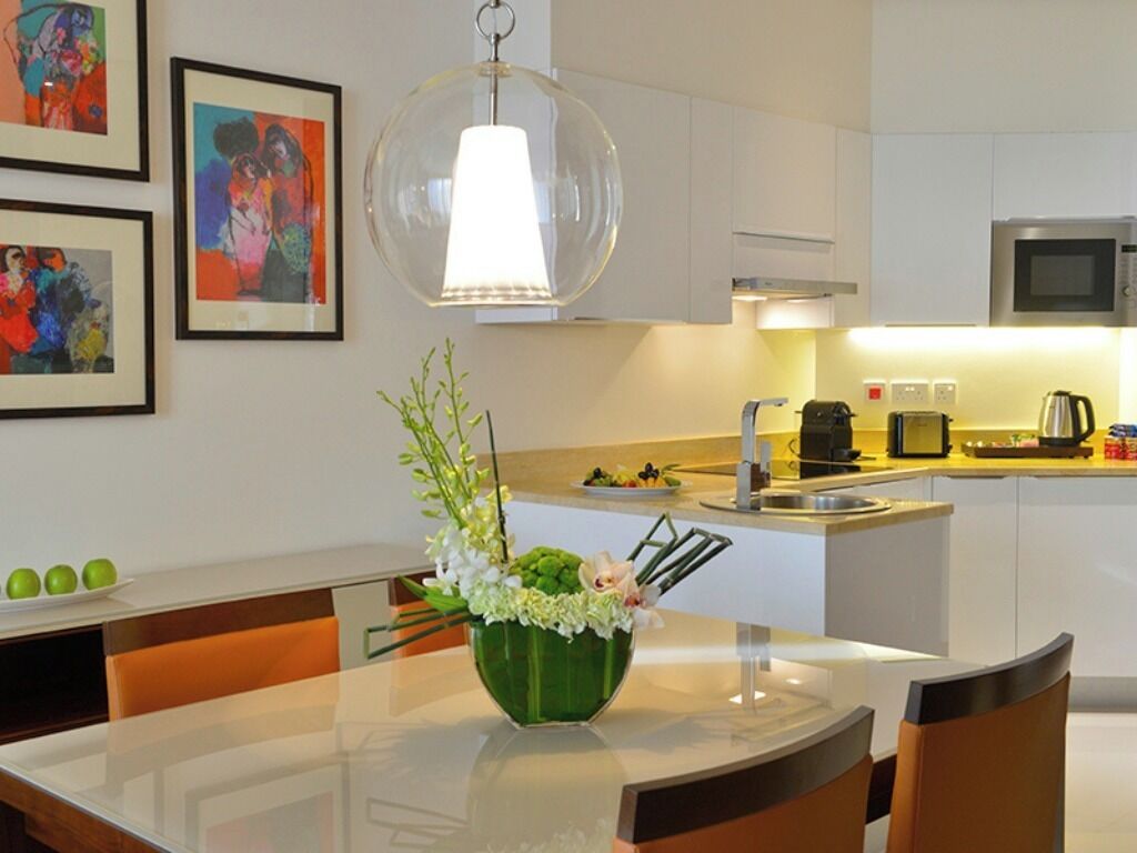 A modern kitchen with white cabinets, a microwave, and a dining area with a table and chairs.