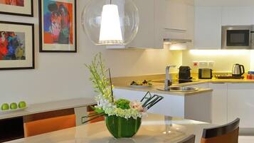 Una cocina moderna con armarios blancos, microondas y un comedor con mesa y sillas.