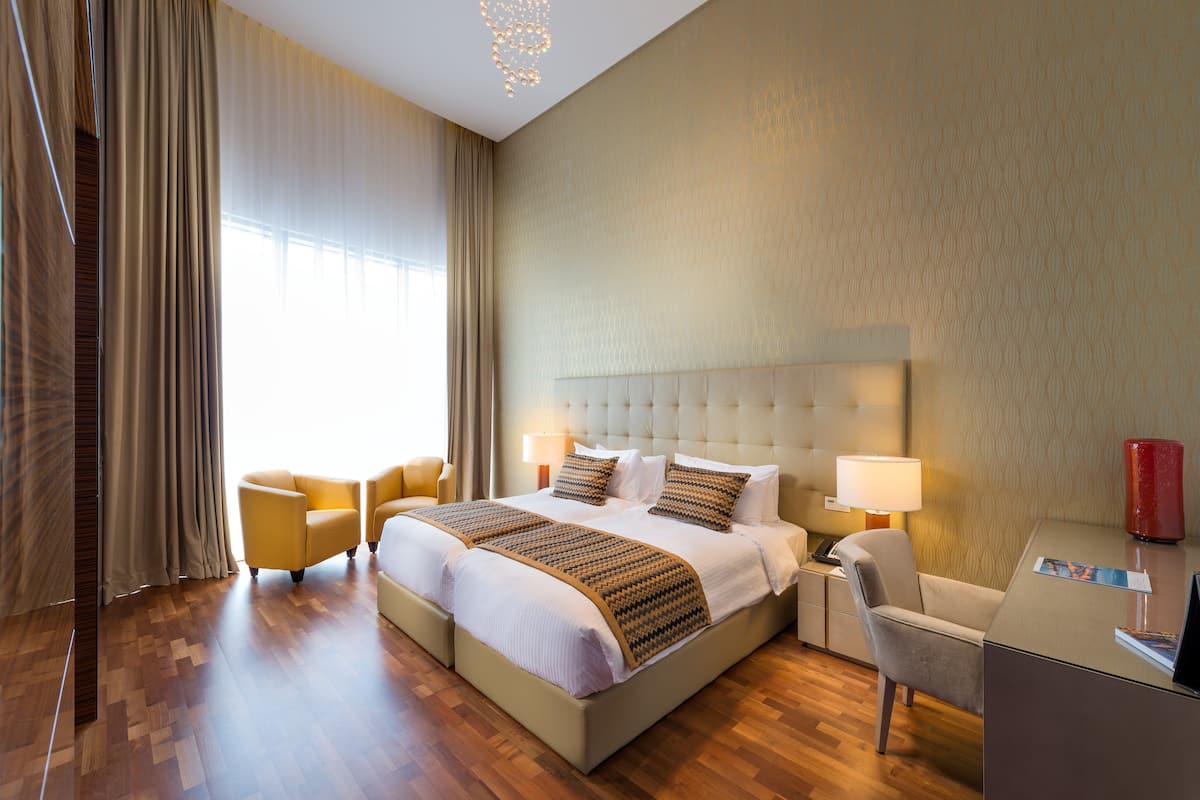 A hotel room with a large bed, two bedside tables, a desk, and a chair.