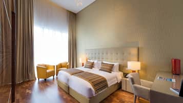 Et hotelværelse med en stor seng, to sengeborde, et skrivebord og en stol.