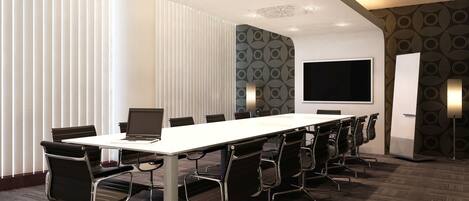 A conference room with a long table, black chairs, a large screen, and patterned walls.