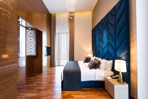 Una habitación de hotel moderna con una cama grande, una mesita de noche con lámpara y un panel decorativo en la pared.