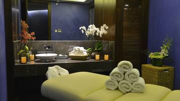 Bathroom features a sink with a countertop, a large mirror, and two potted plants.