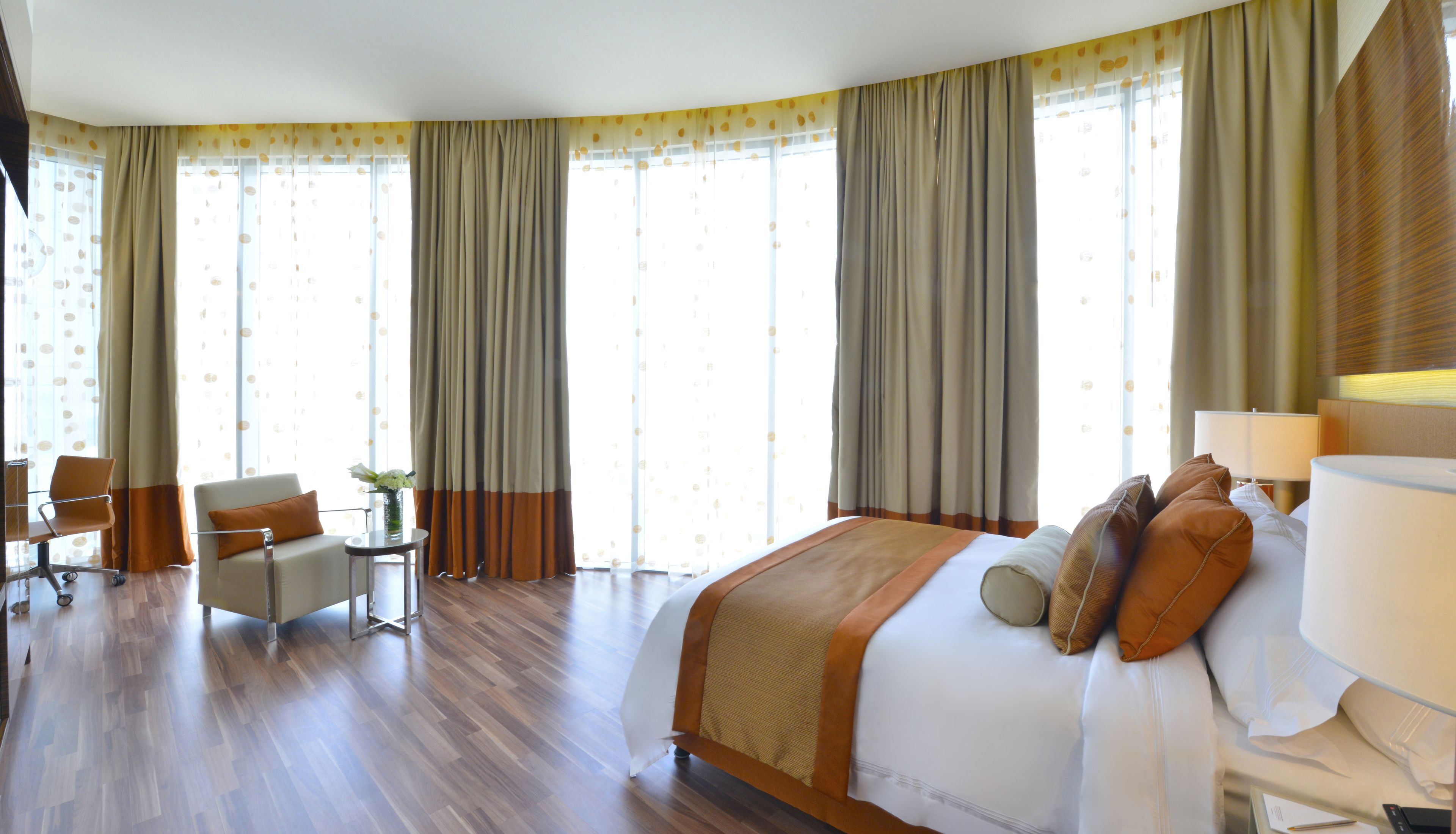 Ein Hotelzimmer mit einem großen Bett, einem Schreibtisch, einem Stuhl und einem fenster mit Vorhängen.