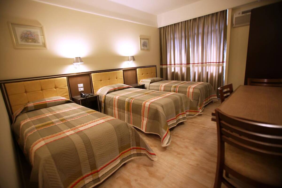 A hotel room with two beds, a wooden table, and a chair.