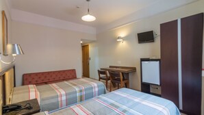 Ein Hotelzimmer mit zwei Betten, einem Schreibtisch, einem Stuhl, einem Fernseher und einem Kleiderschrank.
