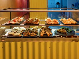 Buffet com diversos alimentos expostos em uma vitrine de vidro.