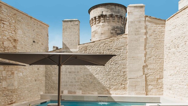En bygning i sten med pool og loungeområde.