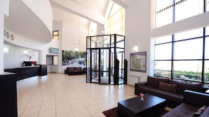 A spacious living area with a large glass partition, a reception desk, a sofa, and a coffee table. - Farah Inn Ifrane (Ifrane)