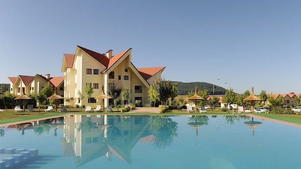 A resort with a swimming pool, multiple buildings, and lounge chairs. - Farah Inn Ifrane (Ifrane)