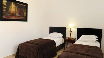 A hotel room with two beds, a nightstand with a lamp, and a painting on the wall.