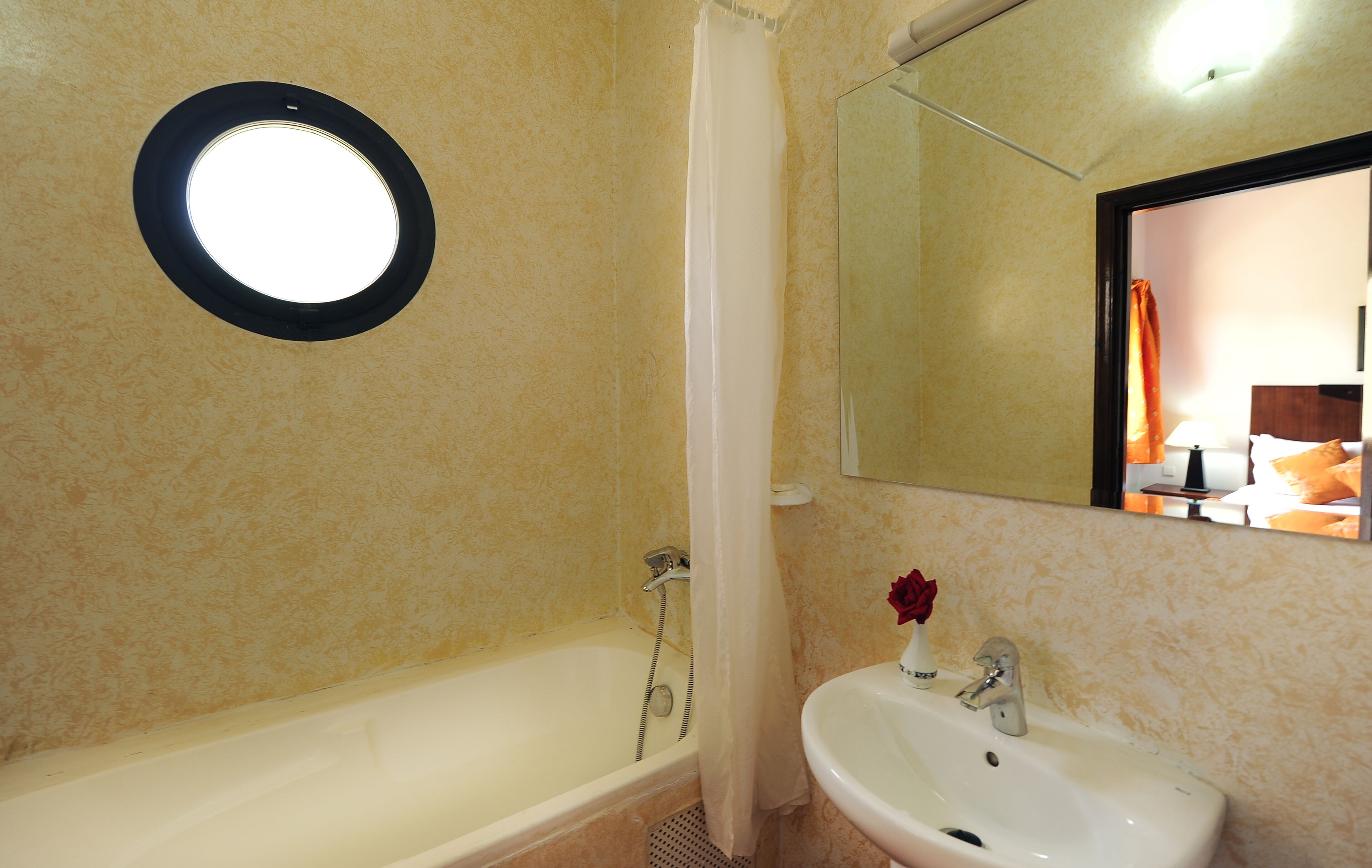 A bathroom with a bathtub, a sink, a mirror, and a circular light fixture.