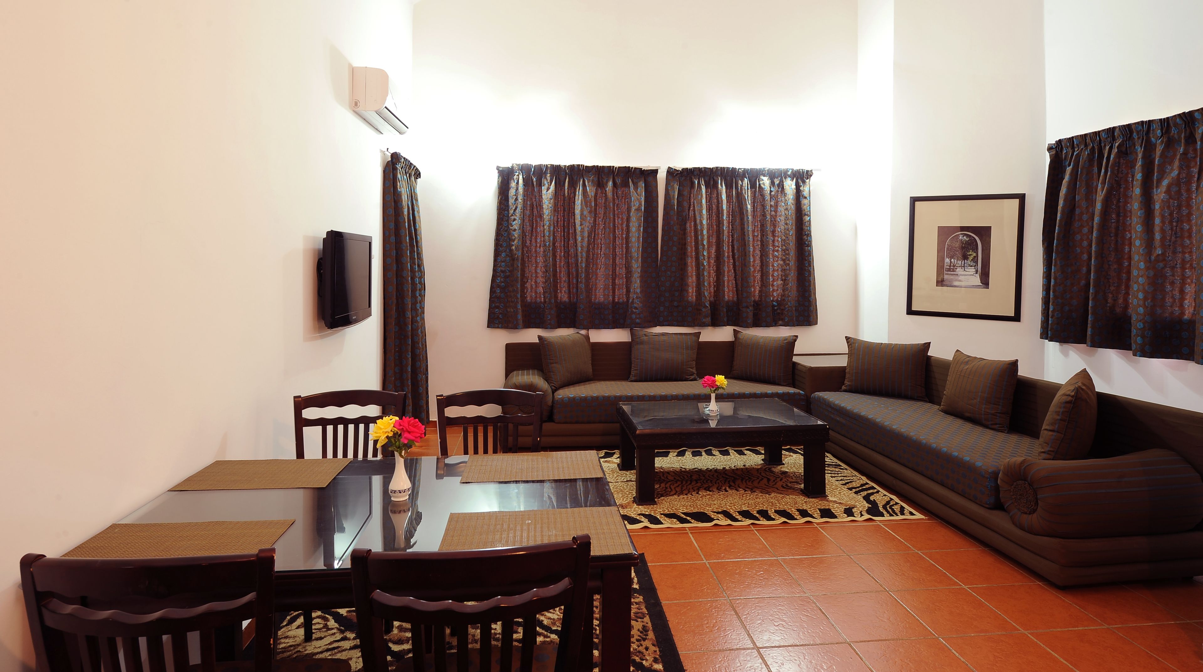 A living room with a sofa, chairs, a coffee table, a TV, and patterned curtains.