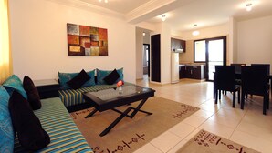 A modern living room with a sofa, coffee table, and a dining area with chairs and a table. - Farah Inn Ifrane (Ifrane)