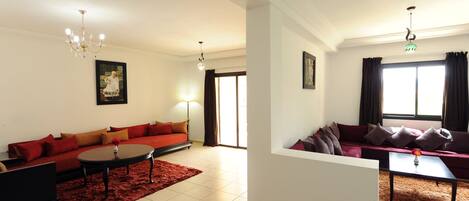 A spacious living room with a red sofa, a black coffee table, and a chandelier.