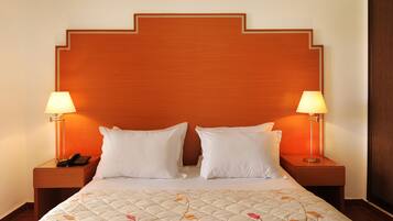 Een hotelkamer met een groot bed, twee bedlampen, een telefoon en een houten hoofdeinde.