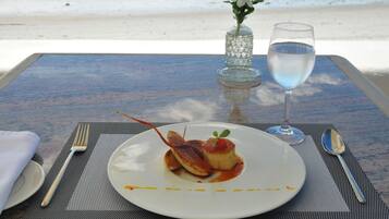 A table set with a plate of food, a glass of water, and a vase with flowers.