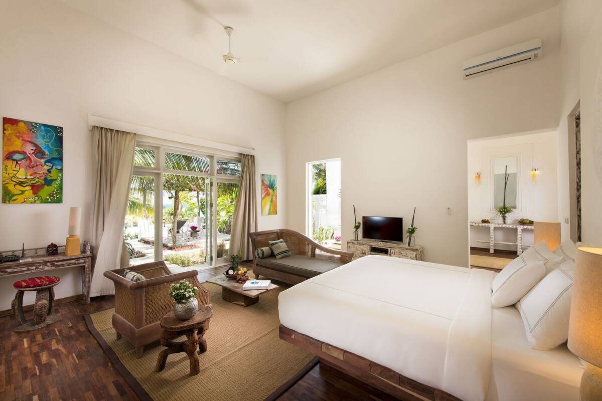 A hotel room with a bed, sofa, TV, and a desk with a computer.