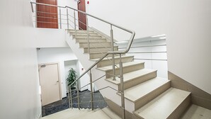 A staircase with metal railings and beige steps leading to an upper floor. - Mosaic Hotel (Riga)