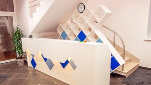 A reception desk with a geometric design, a staircase, and a clock on the wall. - Mosaic Hotel (Riga)