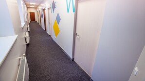 A hallway with doors labeled "WC" and "W.C." and a radiator on the left. - Mosaic Hotel (Riga)