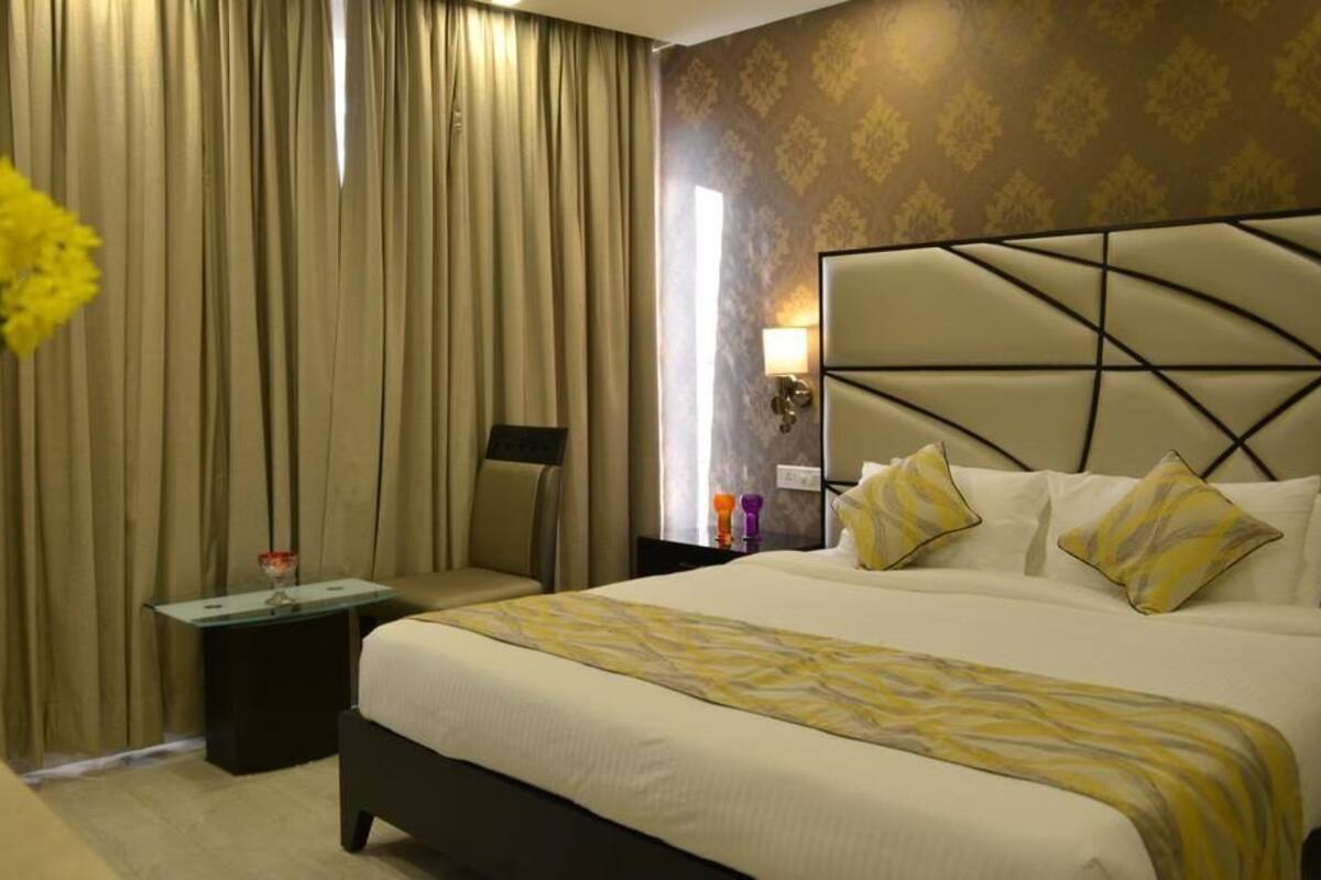 Habitación de hotel con una cama grande, una mesita de noche, una lámpara y un accesorio de luz en la pared.