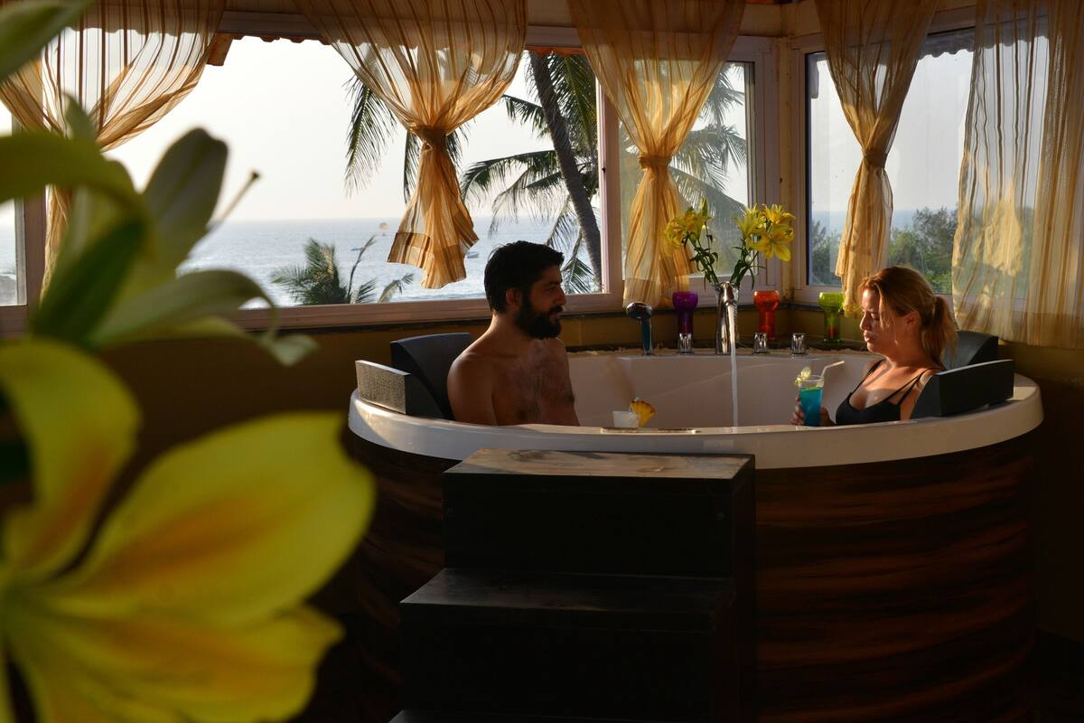 Una pareja en un jacuzzi con vista al océano.