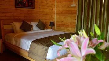 A wooden-paneled room with a bed, pillows, a nightstand, a lamp, and a framed picture on the wall.