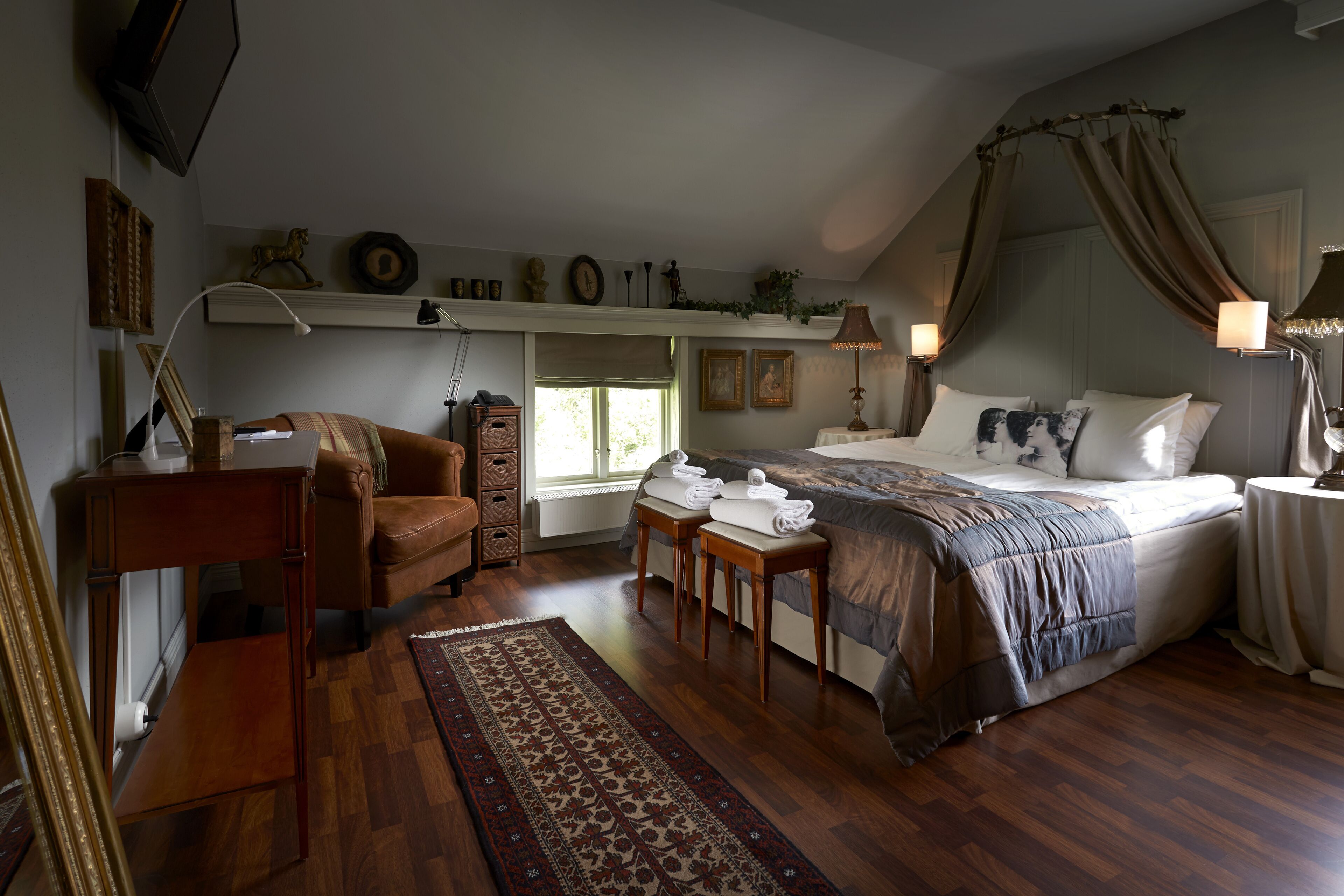 Ein Schlafzimmer mit einem großen Bett, einem Schreibtisch, einem Stuhl, einem Fenster und einem Deckenventilator.