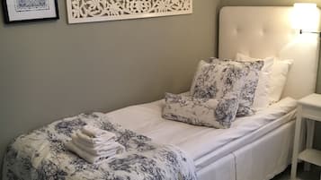 A neatly made bed with floral bedding, a decorative wall panel, and a framed picture.