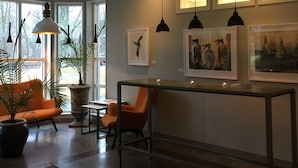 Un interior moderno con techo alto, iluminación colgante, una mesa central y obras de arte en las paredes.