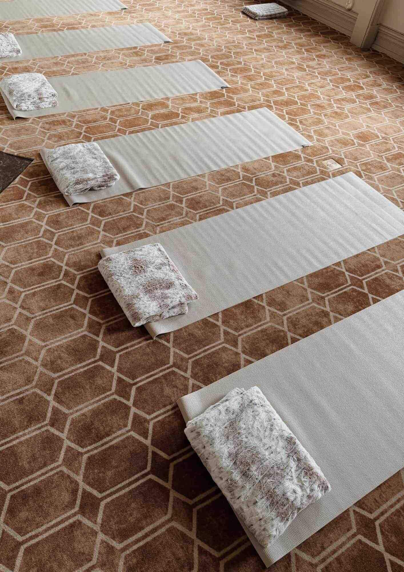 A room with a patterned carpet and several neatly folded mats arranged in a row.