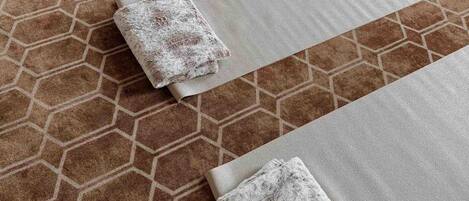 A room with a patterned carpet and several neatly folded mats arranged in a row.