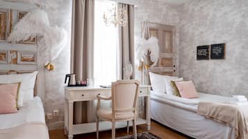 A bedroom with two beds, a desk, and a chair. There are feather decorations on the walls and a chandelier.
