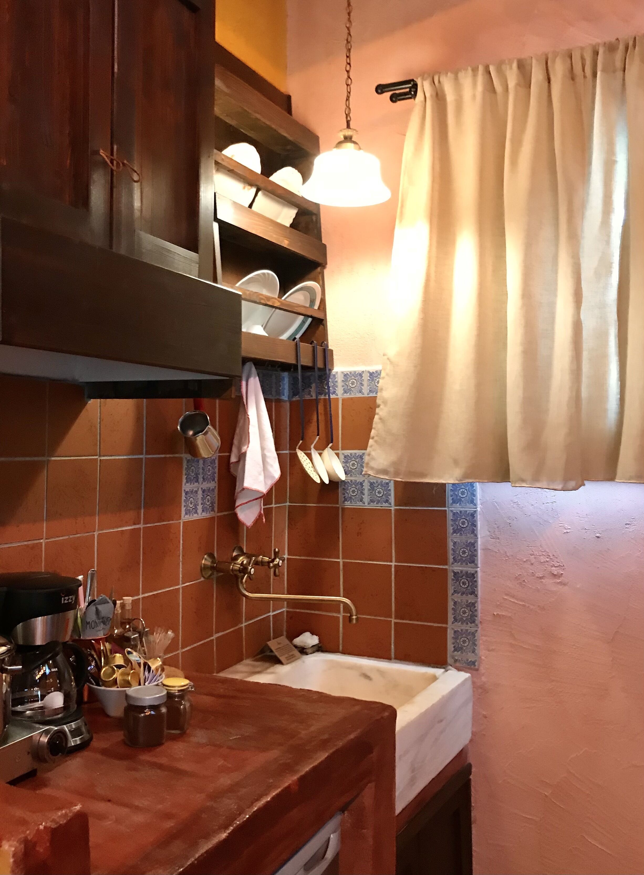 A compact kitchen with a wooden countertop, a sink, and a hanging light fixture.