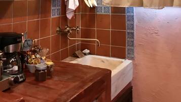 A compact kitchen with a wooden countertop, a sink, and a hanging light fixture.