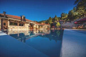 Una piscina techada, una piscina al aire libre, sombrillas