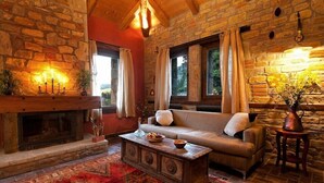 A cozy room with a stone fireplace, a sofa, and a coffee table. - Montanema Handmade Village (Mouzaki)